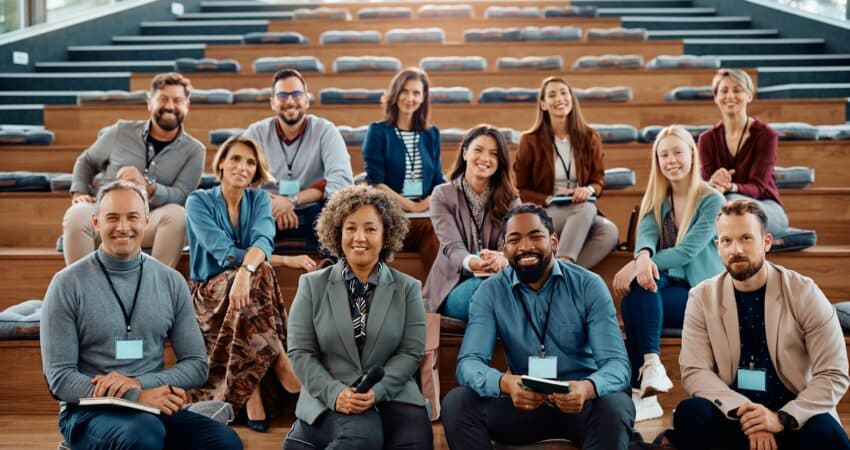 Multiracial group of happy business seminar attendees at convention center looking at camera.